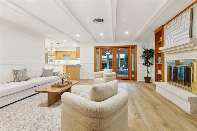 4905 Haring Ct, Metairie, LA 70006 - living room featuring french doors, light wood-style floors, beam ceiling, recessed lighting, and a fireplace