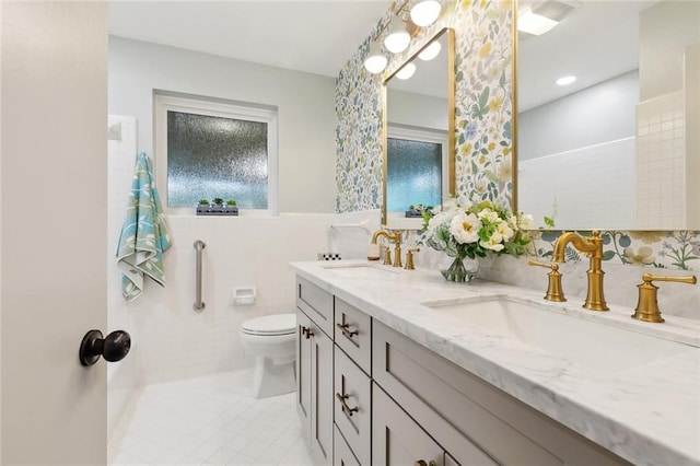 4905 Haring Ct, Metairie, LA 70006 - full bathroom featuring double vanity, tile walls, tile patterned flooring, toilet, and a wainscoted wall
