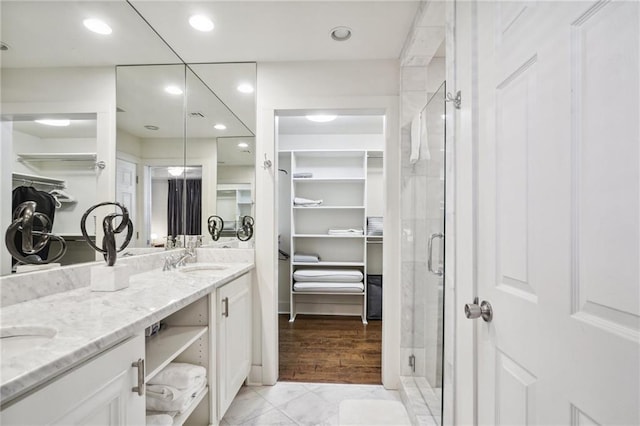 5727 Fleur De Lis Dr, New Orleans, LA 70124 - bathroom featuring a walk in closet, double vanity, a stall shower, marble finish flooring, and recessed lighting