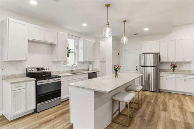 2641 Anchor Dr, Marrero, LA 70072 - kitchen with stainless steel appliances, a sink, a breakfast bar, white cabinetry, and a kitchen island