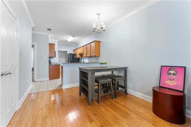 5315 Arlington Ct, Baton Rouge, LA 70820 - kitchen with freestanding refrigerator, a chandelier, light wood-type flooring, ornamental molding, and brown cabinets