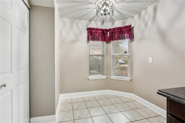 139 Avant Garde Cir Unit 139, Kenner, LA 70065 - unfurnished dining area featuring light tile patterned floors, baseboards, a textured ceiling, and a chandelier