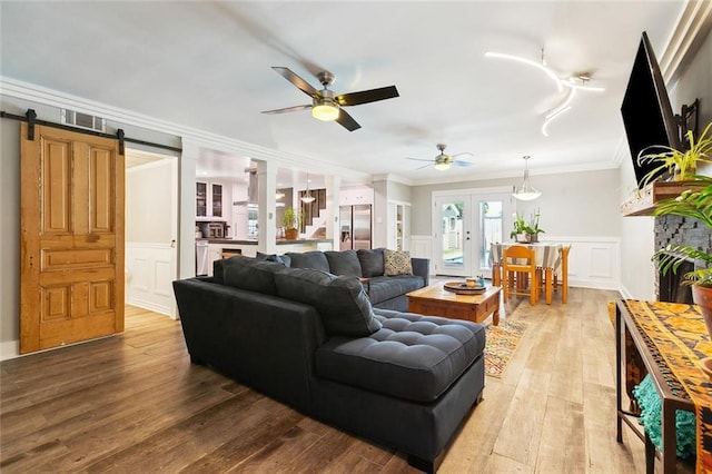 623 Bonnabel Blvd, Metairie, LA 70005 - living room featuring a decorative wall, ornamental molding, light wood-style flooring, wainscoting, and a ceiling fan
