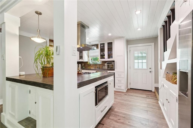 623 Bonnabel Blvd, Metairie, LA 70005 - kitchen with island range hood, stainless steel microwave, wood counters, glass insert cabinets, and light wood-style floors