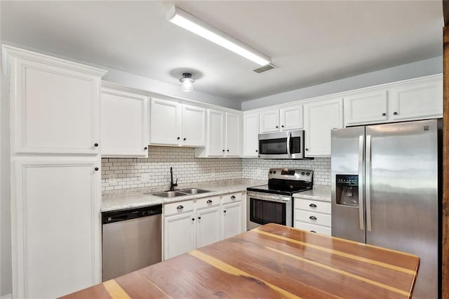 185 Lark St, Slidell, LA 70460 - kitchen with appliances with stainless steel finishes, a sink, white cabinets, and tasteful backsplash