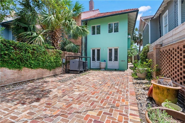 2627 S Carrollton Ave, New Orleans, LA 70118 - back of house with french doors, stucco siding, a patio area, a tile roof, and cooling unit