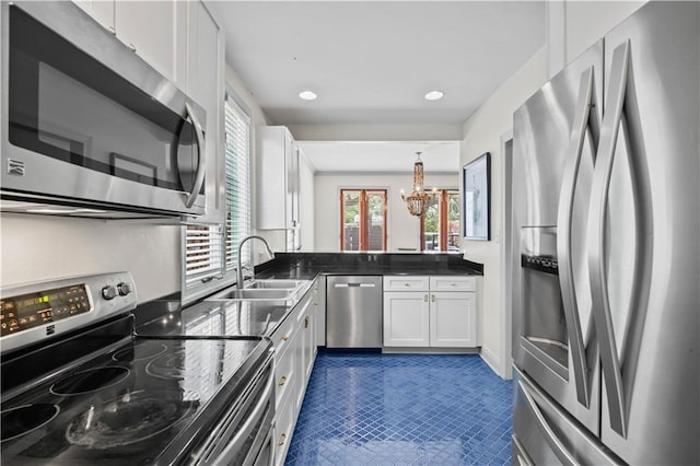 2627 S Carrollton Ave, New Orleans, LA 70118 - kitchen with stainless steel appliances, a chandelier, white cabinetry, a sink, and dark countertops