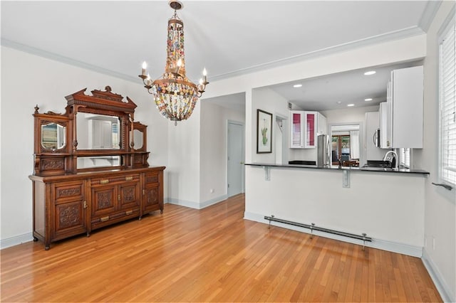 2627 S Carrollton Ave, New Orleans, LA 70118 - kitchen with dark countertops, a chandelier, light wood-type flooring, white cabinets, and a peninsula