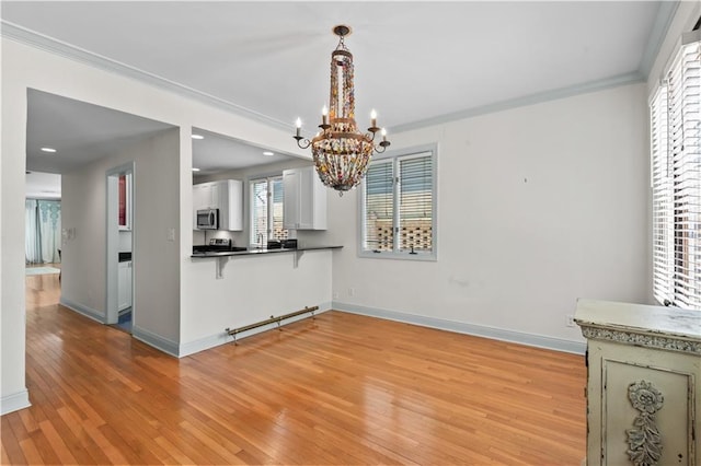 2627 S Carrollton Ave, New Orleans, LA 70118 - kitchen featuring stainless steel microwave, a chandelier, light wood-style floors, a breakfast bar, and crown molding