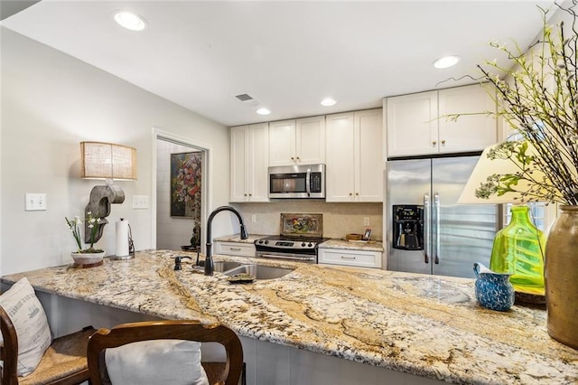 8 S Court Villa Unit 8, Mandeville, LA 70471 - kitchen featuring stainless steel appliances, a sink, light stone countertops, white cabinetry, and recessed lighting
