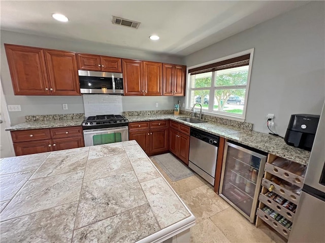6021 Amhurst St, Metairie, LA 70003 - kitchen with stainless steel appliances, a sink, beverage cooler, brown cabinets, and recessed lighting