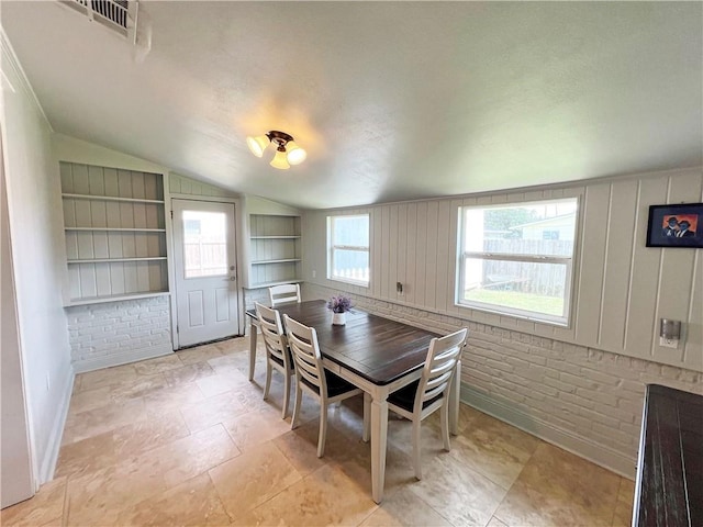 6021 Amhurst St, Metairie, LA 70003 - dining area with lofted ceiling, built in shelves, baseboards, and brick wall