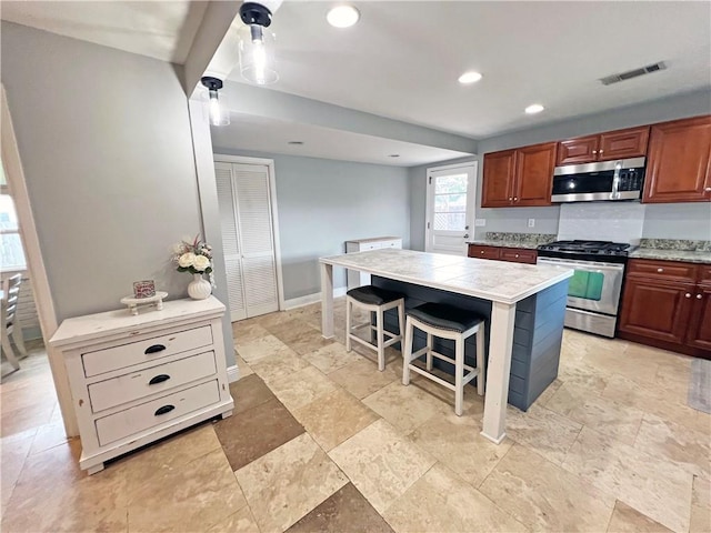 6021 Amhurst St, Metairie, LA 70003 - kitchen with appliances with stainless steel finishes, light countertops, a kitchen bar, recessed lighting, and light stone finish floors