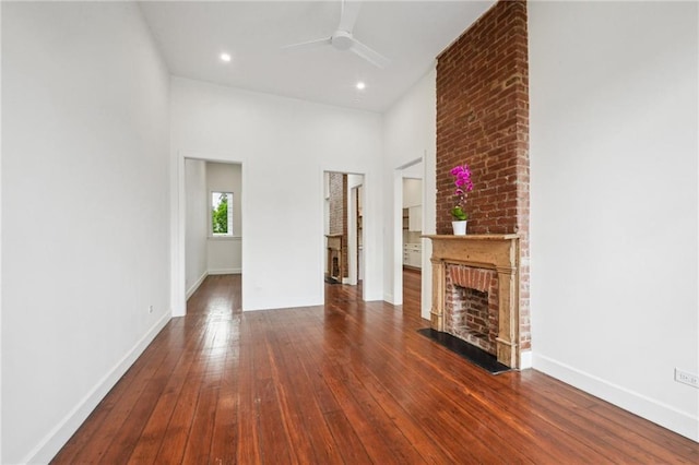 2417 Rousseau St, New Orleans, LA 70130 - unfurnished living room featuring a ceiling fan, a brick fireplace, dark wood-style flooring, baseboards, and recessed lighting