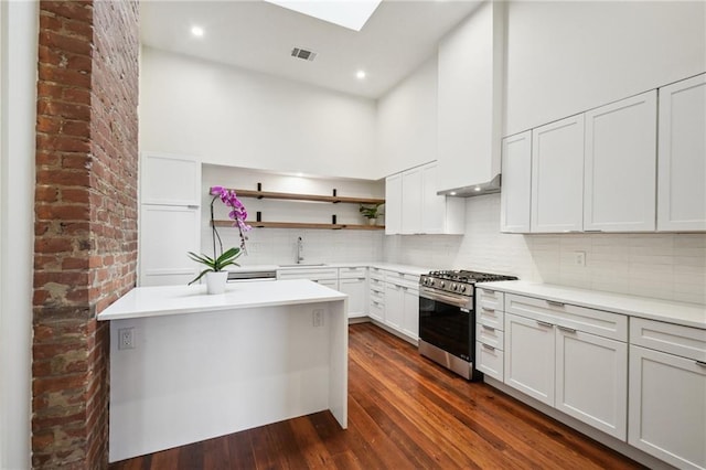 2417 Rousseau St, New Orleans, LA 70130 - kitchen featuring stainless steel gas stove, open shelves, a sink, dark wood finished floors, and decorative backsplash