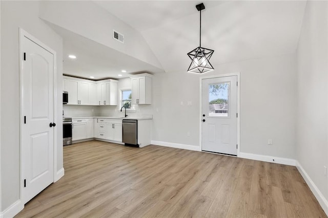 2925 Barataria Blvd, Marrero, LA 70072 - kitchen featuring appliances with stainless steel finishes, light countertops, light wood-style floors, lofted ceiling, and white cabinetry