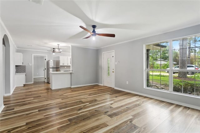 112 Oakwood Dr, Slidell, LA 70460 - unfurnished living room with ceiling fan, arched walkways, crown molding, wood finished floors, and baseboards
