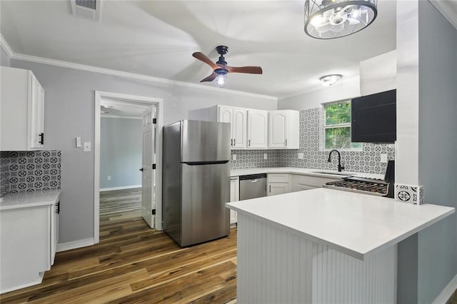 112 Oakwood Dr, Slidell, LA 70460 - kitchen with stainless steel appliances, a sink, a peninsula, dark wood finished floors, and white cabinets