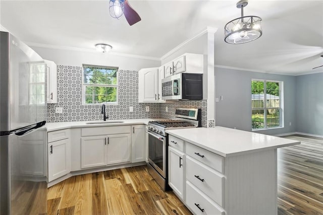 112 Oakwood Dr, Slidell, LA 70460 - kitchen featuring stainless steel appliances, a sink, a ceiling fan, ornamental molding, and a peninsula