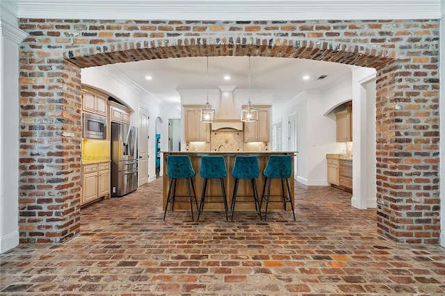 126 Tchefuncta Dr S, Covington, LA 70433 - kitchen with appliances with stainless steel finishes, brick flooring, a breakfast bar, a center island with sink, and arched walkways