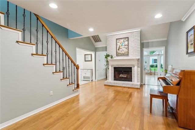 203 Willow Cir, Mandeville, LA 70471 - living area with a brick fireplace, light wood-style flooring, stairs, baseboards, and ornamental molding