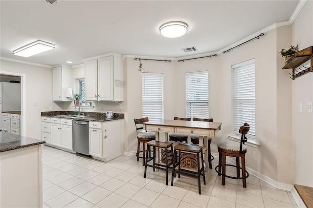 203 Willow Cir, Mandeville, LA 70471 - kitchen with stainless steel dishwasher, white cabinetry, a sink, baseboards, and crown molding