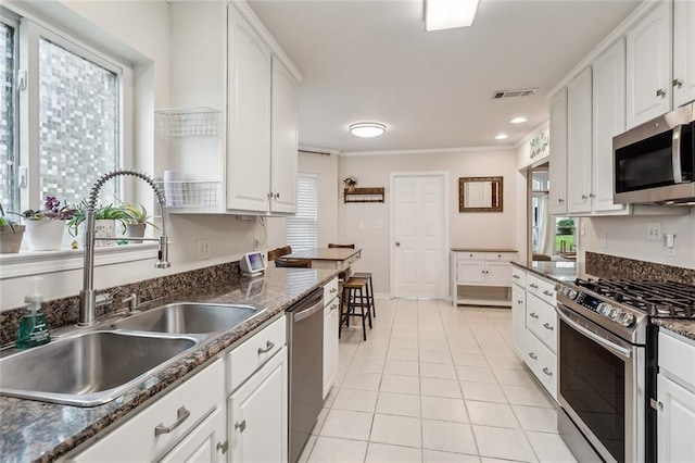 203 Willow Cir, Mandeville, LA 70471 - kitchen featuring stainless steel appliances, a sink, light tile patterned floors, healthy amount of natural light, and ornamental molding