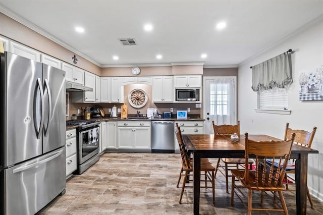 929 Carnation Ave, Metairie, LA 70001 - kitchen with stainless steel appliances, ornamental molding, dark countertops, under cabinet range hood, and white cabinets
