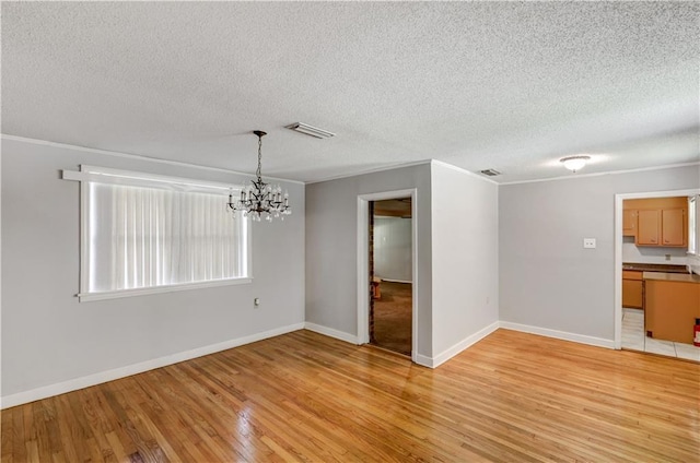 105 Norland Ave, New Orleans, LA 70131 - empty room with a chandelier, crown molding, light wood-style flooring, and a textured ceiling