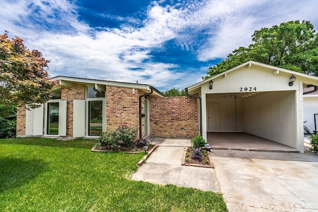 2924 Elizabeth St, Metairie, LA 70003 - mid-century modern home with concrete driveway, a front yard, a carport, and brick siding