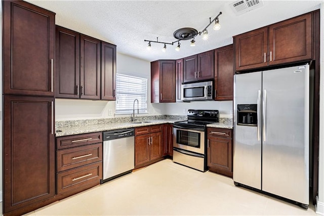 2924 Elizabeth St, Metairie, LA 70003 - kitchen with stainless steel appliances, a sink, light stone countertops, dark brown cabinets, and a textured ceiling