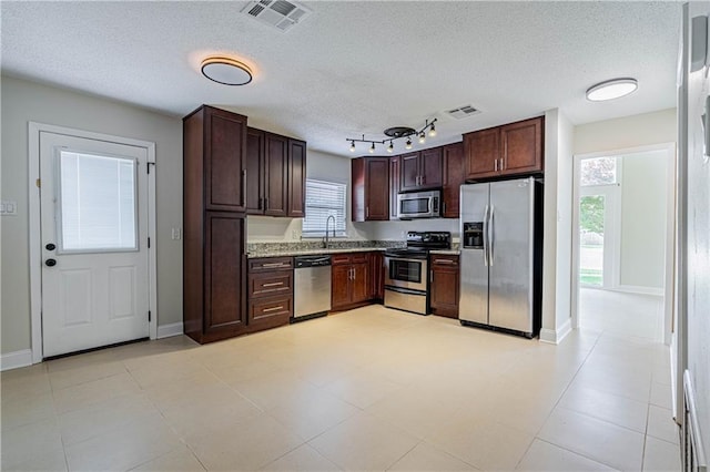 2924 Elizabeth St, Metairie, LA 70003 - kitchen featuring appliances with stainless steel finishes, a sink, a textured ceiling, dark brown cabinets, and baseboards