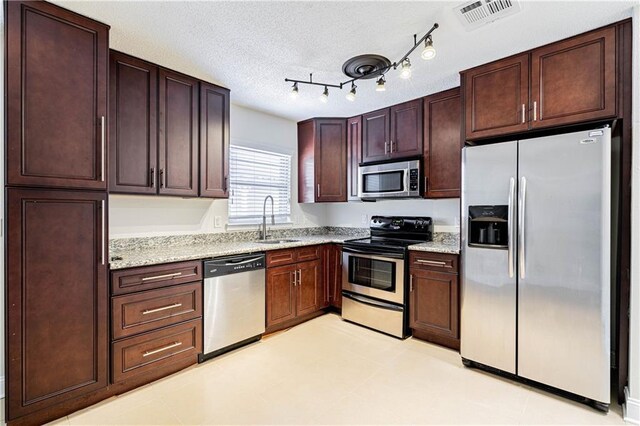2924 Elizabeth St, Metairie, LA 70003 - kitchen with appliances with stainless steel finishes, light stone countertops, dark brown cabinets, and a textured ceiling