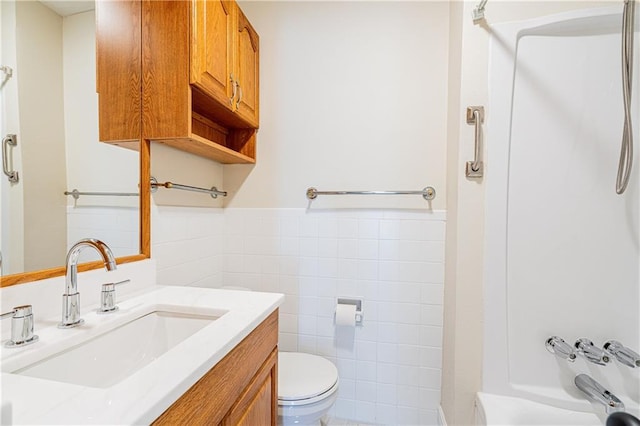 2924 Elizabeth St, Metairie, LA 70003 - bathroom featuring toilet, vanity, tile walls, a wainscoted wall, and shower / washtub combination