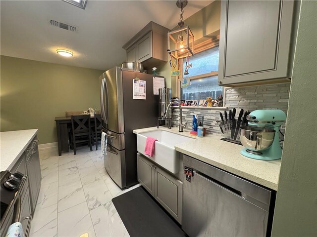 5121 Pike Dr, Metairie, LA 70003 - kitchen featuring appliances with stainless steel finishes, light marble finish flooring, light countertops, and gray cabinetry