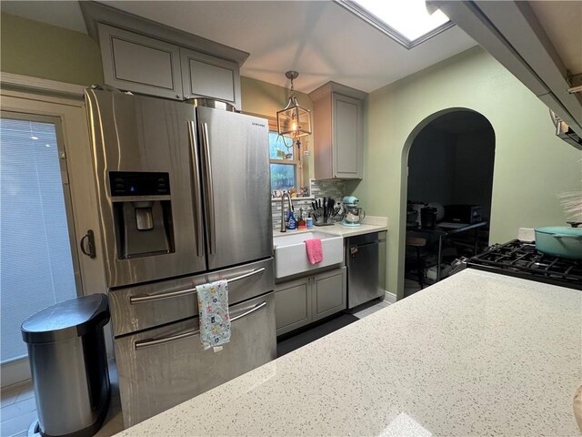 5121 Pike Dr, Metairie, LA 70003 - kitchen featuring appliances with stainless steel finishes, arched walkways, gray cabinetry, pendant lighting, and backsplash