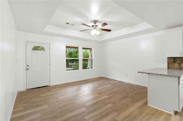 305 S Walnut St, Hammond, LA 70403 - unfurnished living room with a tray ceiling, ceiling fan, light wood-style flooring, and baseboards