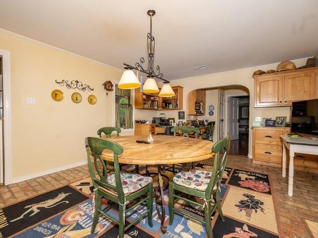 109 Kendrick Dr, Slidell, LA 70461 - dining space featuring brick flooring, arched walkways, ornamental molding, and baseboards