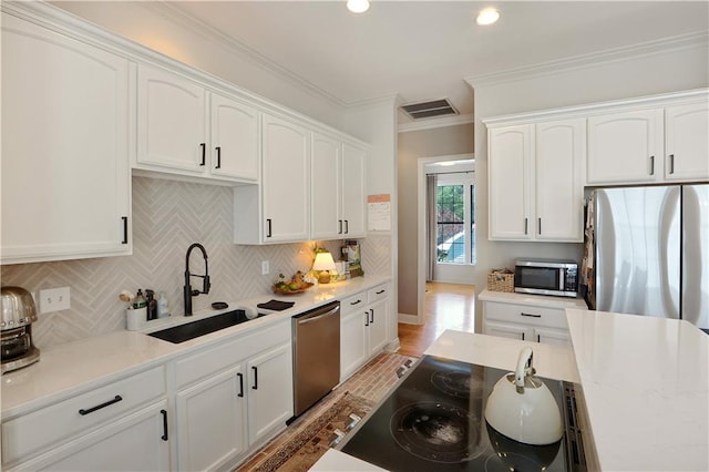 18123 Cusachs Dr, Covington, LA 70433 - kitchen featuring stainless steel appliances, a sink, white cabinets, ornamental molding, and recessed lighting