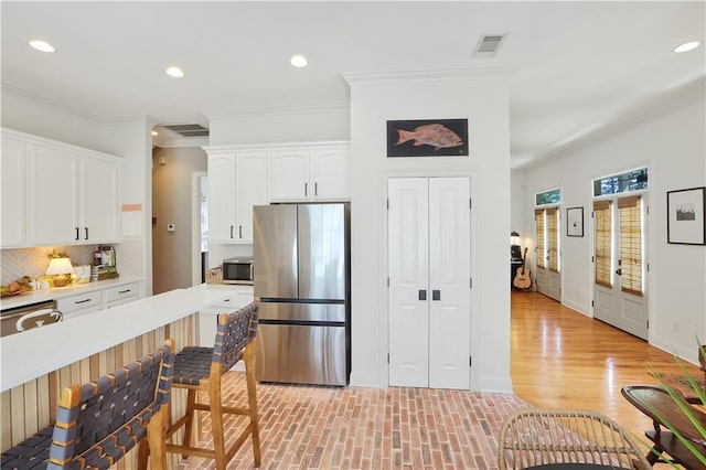 18123 Cusachs Dr, Covington, LA 70433 - kitchen featuring stainless steel appliances, a kitchen breakfast bar, white cabinets, backsplash, and crown molding