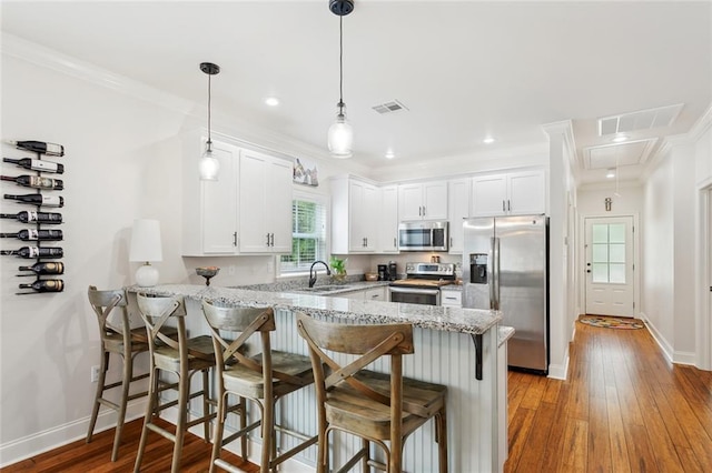 502 W 7th Ave, Covington, LA 70433 - kitchen with stainless steel appliances, a peninsula, white cabinetry, a breakfast bar area, and a sink