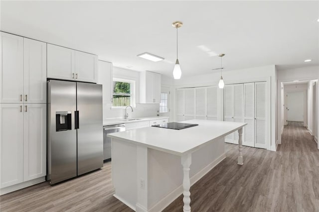 351 Huntington Dr, Slidell, LA 70458 - kitchen featuring stainless steel appliances, a sink, light wood-style floors, white cabinetry, and a center island