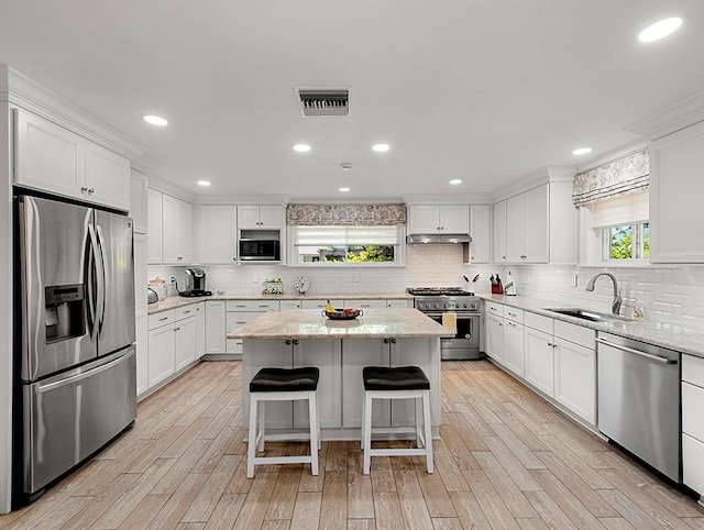 1104 Sena Dr, Metairie, LA 70005 - kitchen featuring appliances with stainless steel finishes, backsplash, under cabinet range hood, a center island, and recessed lighting