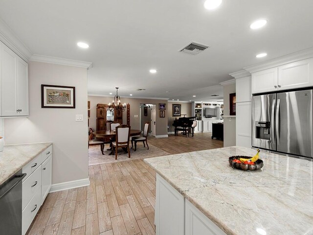 1104 Sena Dr, Metairie, LA 70005 - kitchen with stainless steel appliances, recessed lighting, ornamental molding, light wood finished floors, and white cabinets