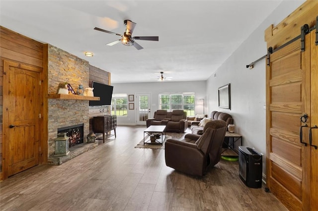 23375 Lowe Davis Rd, Covington, LA 70435 - living room featuring a barn door, a ceiling fan, a fireplace, and wood finished floors
