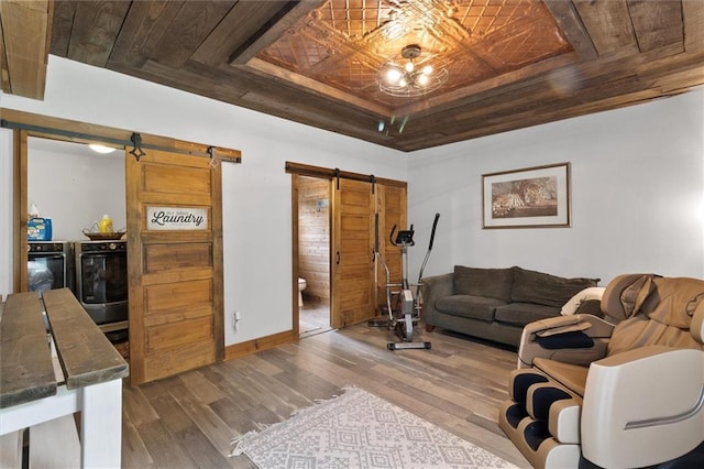 23375 Lowe Davis Rd, Covington, LA 70435 - living room with a barn door, wood finished floors, a tray ceiling, and baseboards