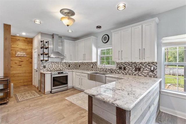 23375 Lowe Davis Rd, Covington, LA 70435 - kitchen with stainless steel stove, wall chimney range hood, a sink, a peninsula, and white cabinets