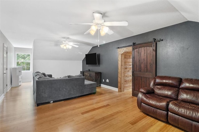 23375 Lowe Davis Rd, Covington, LA 70435 - living room with lofted ceiling, light wood-style floors, ceiling fan, a barn door, and baseboards