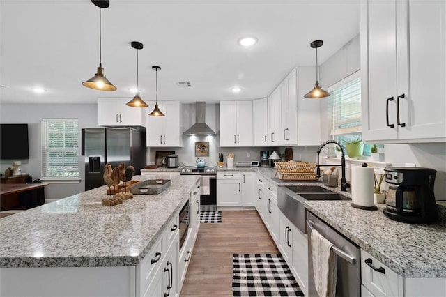 23375 Lowe Davis Rd, Covington, LA 70435 - kitchen with appliances with stainless steel finishes, a sink, wall chimney range hood, a center island, and white cabinets