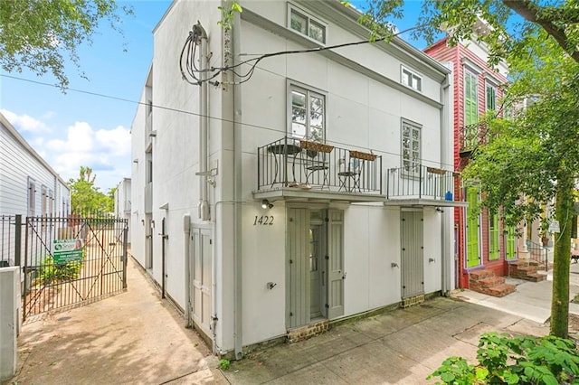 1422 Dauphine St Unit 8, New Orleans, LA 70116 - back of house with a gate, stucco siding, and a balcony